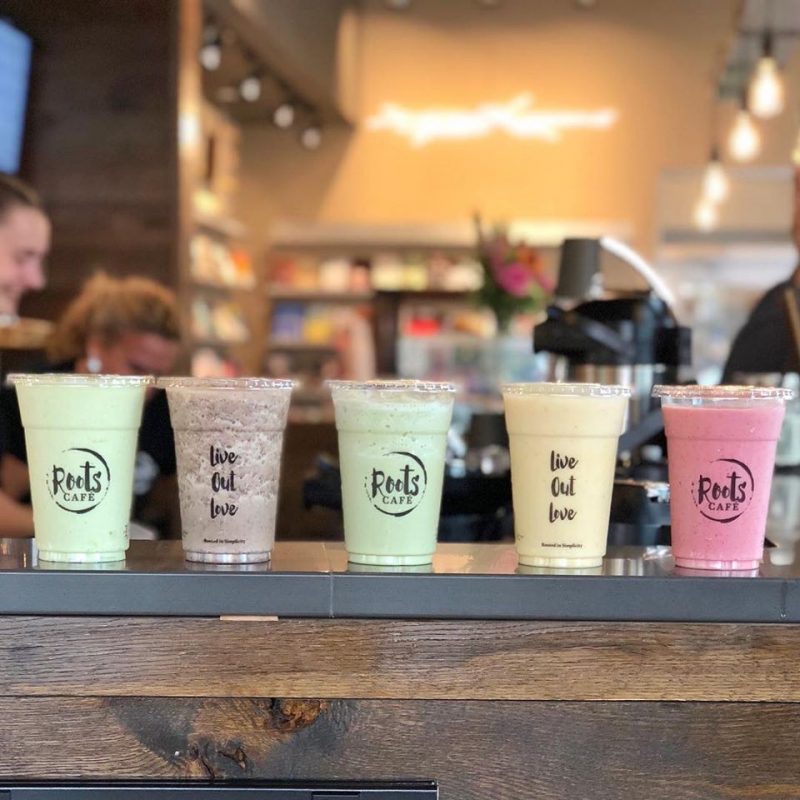 A flight of smoothies in Roots Café cups printed with 'live out love' on the cafe counter