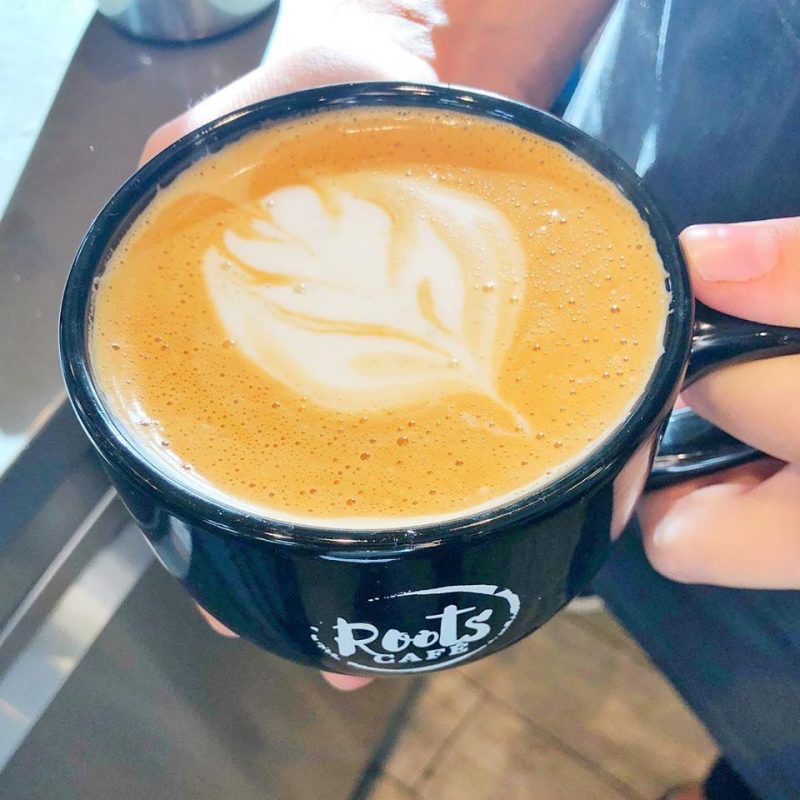 Latte art in a black Roots Café mug